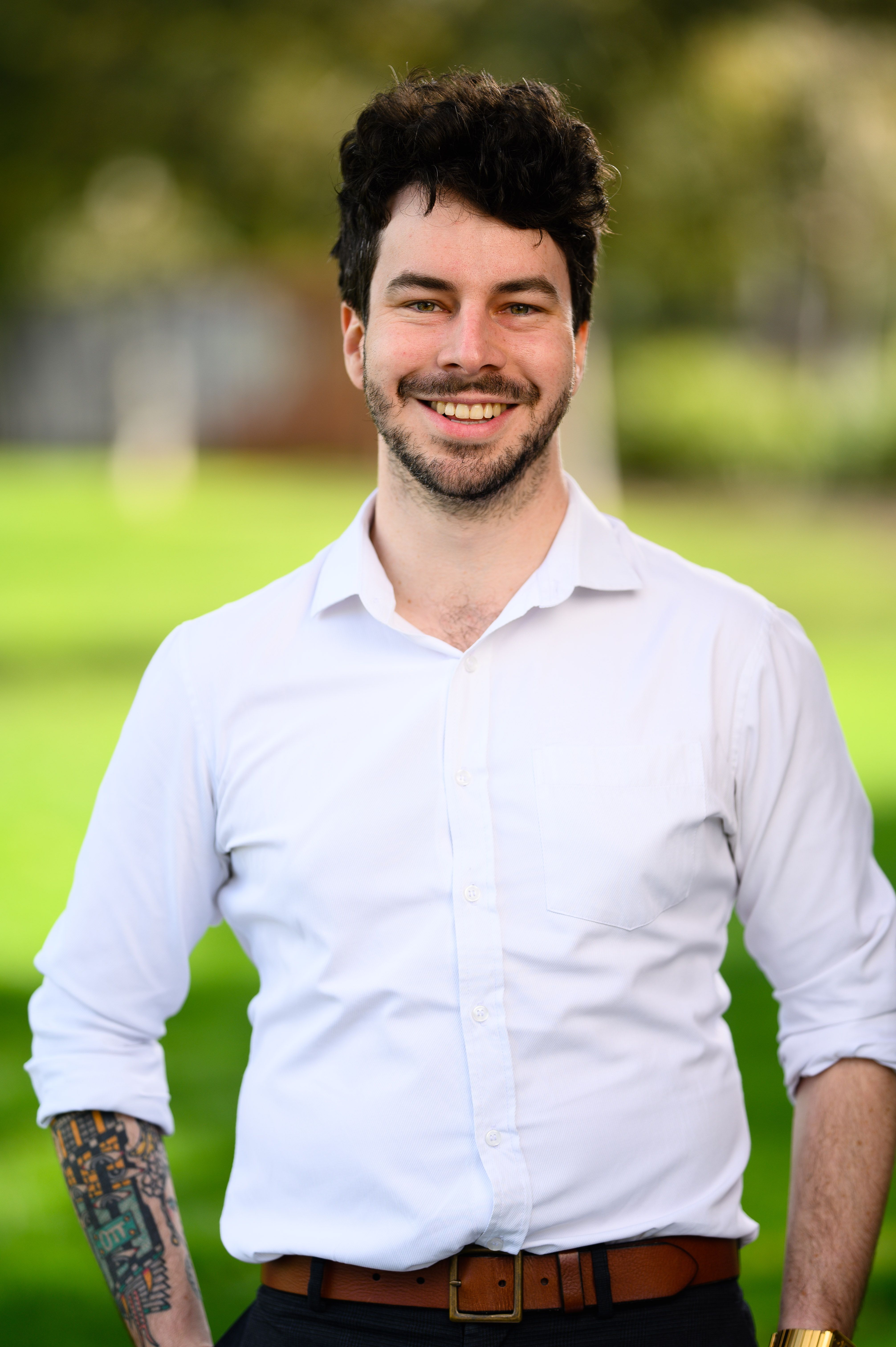 Greens state candidate Mitchell Fuller stands against a background of trees.