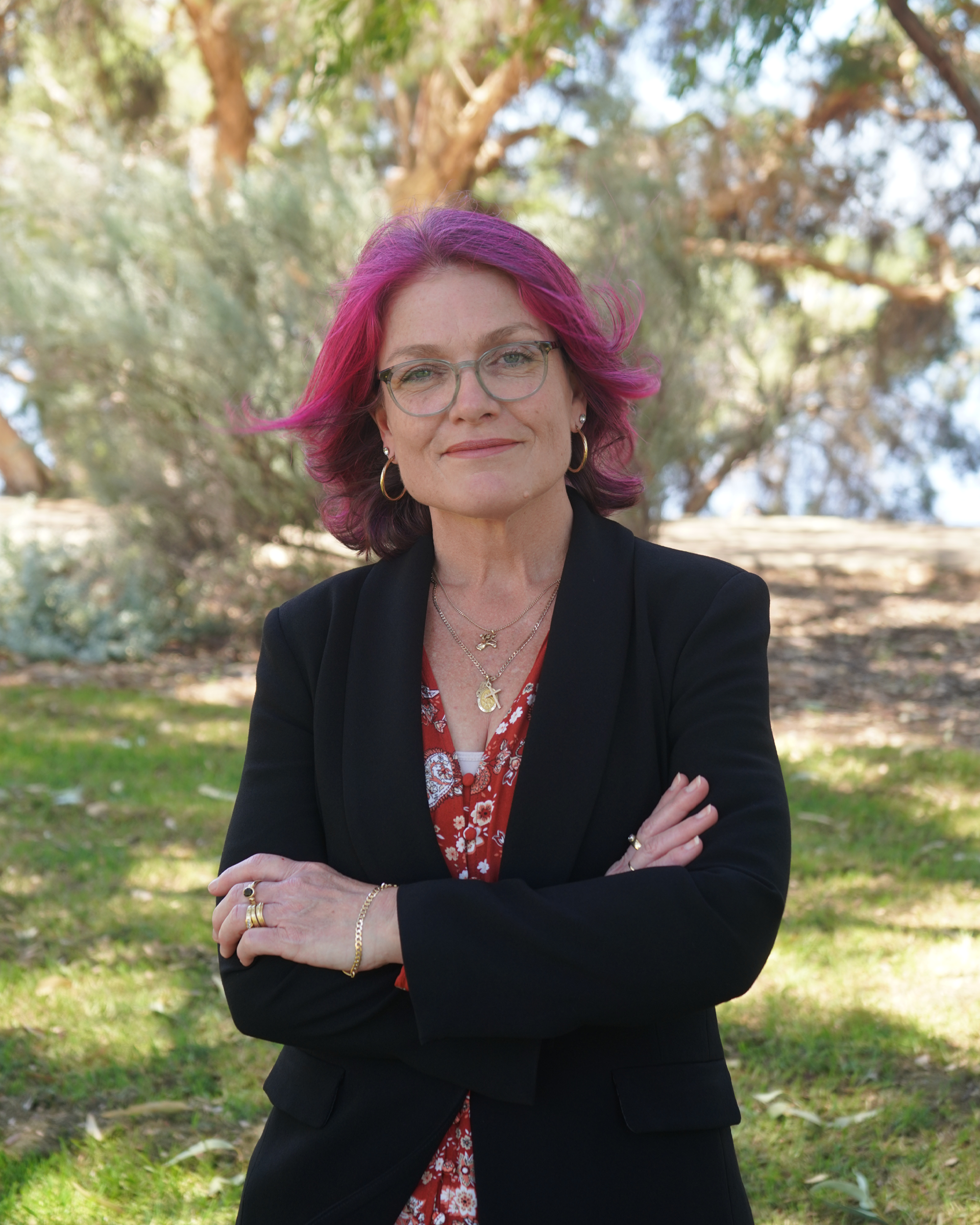 Christine Terrantroy a white woman with purple hair stands with her arms crossed