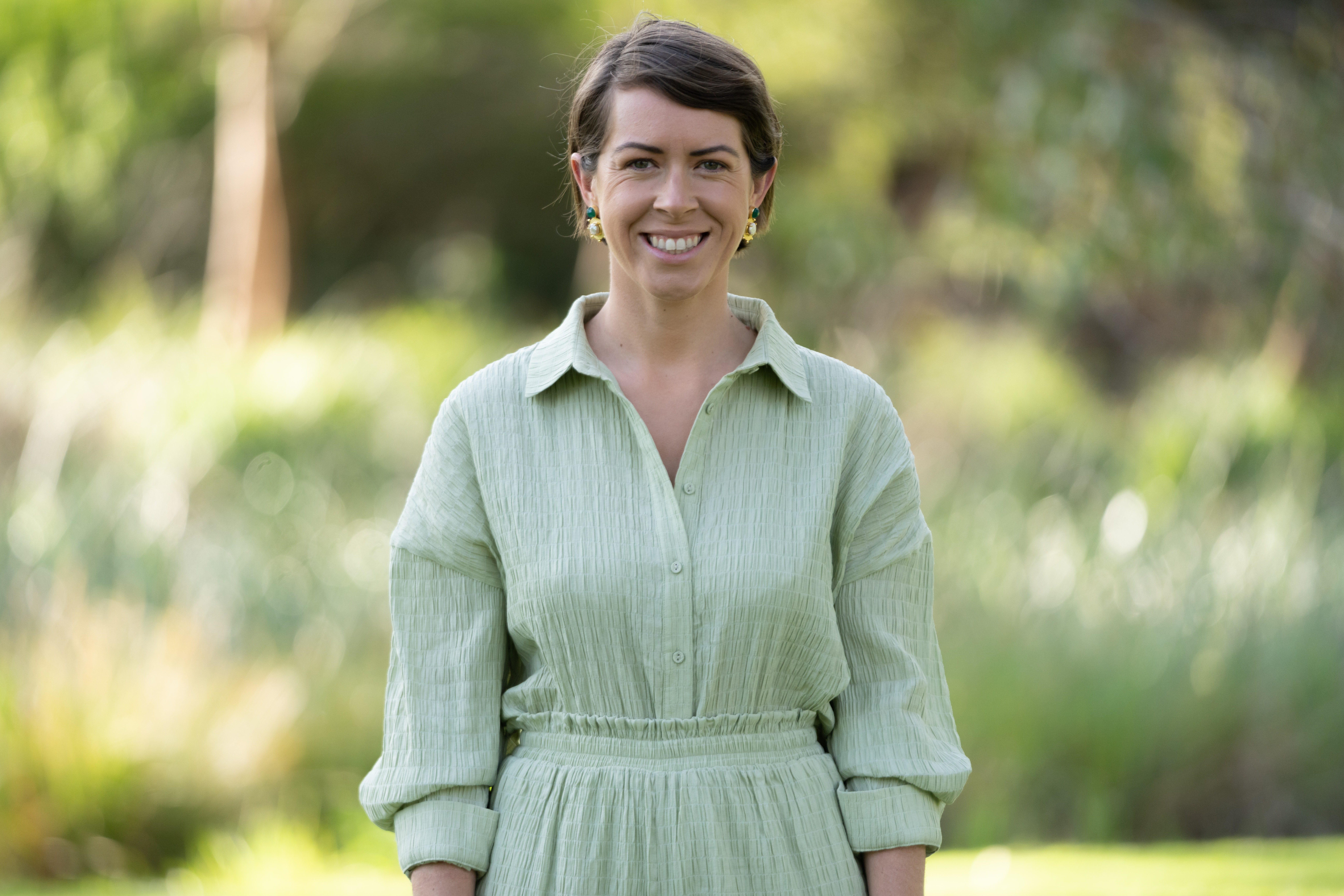Greens state candidate Aleisha Smith stands against a background of trees.