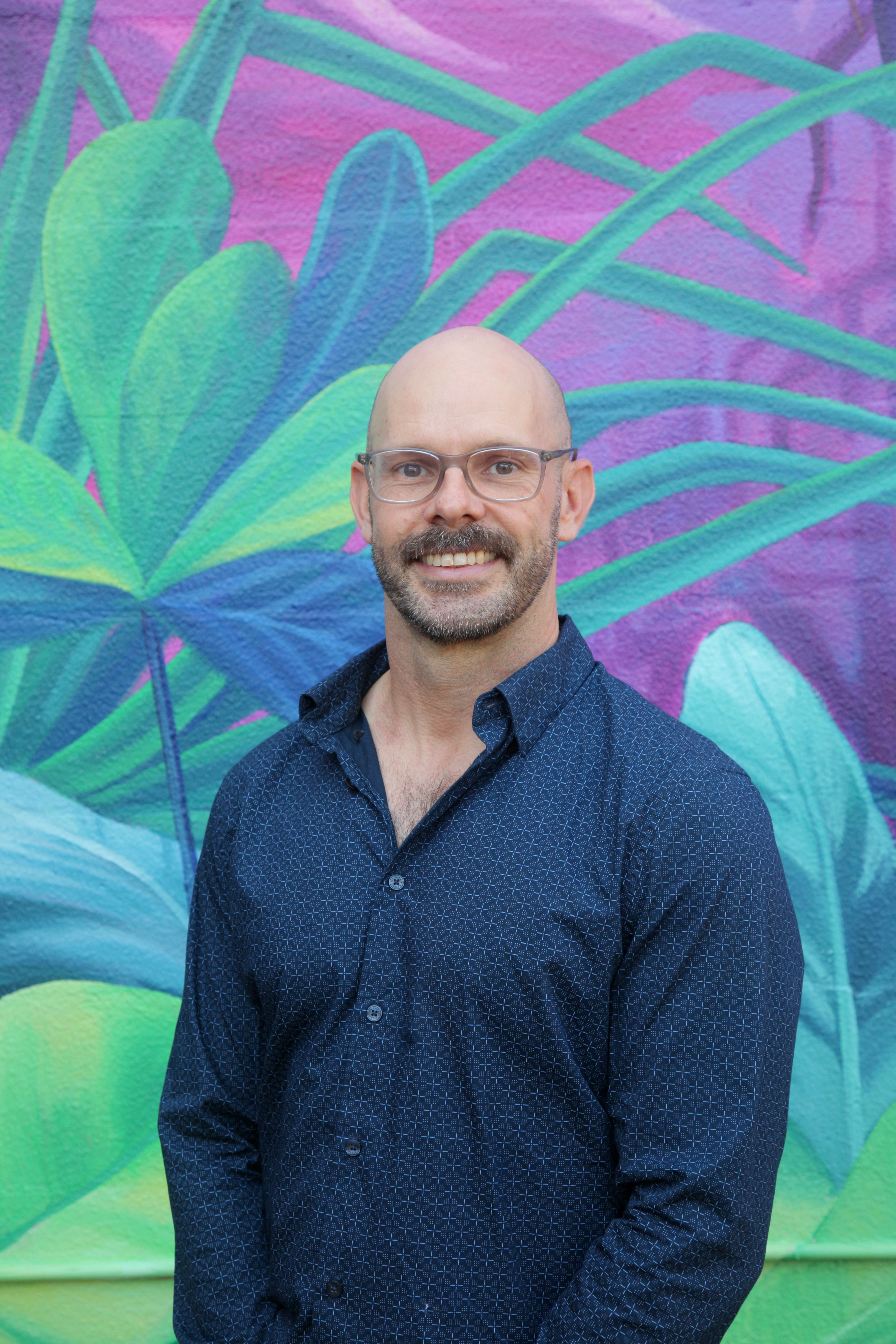 A photo of Greens Candidate for Port Darwin, Greg Dickson in front of colourful street art in Darwin CBD