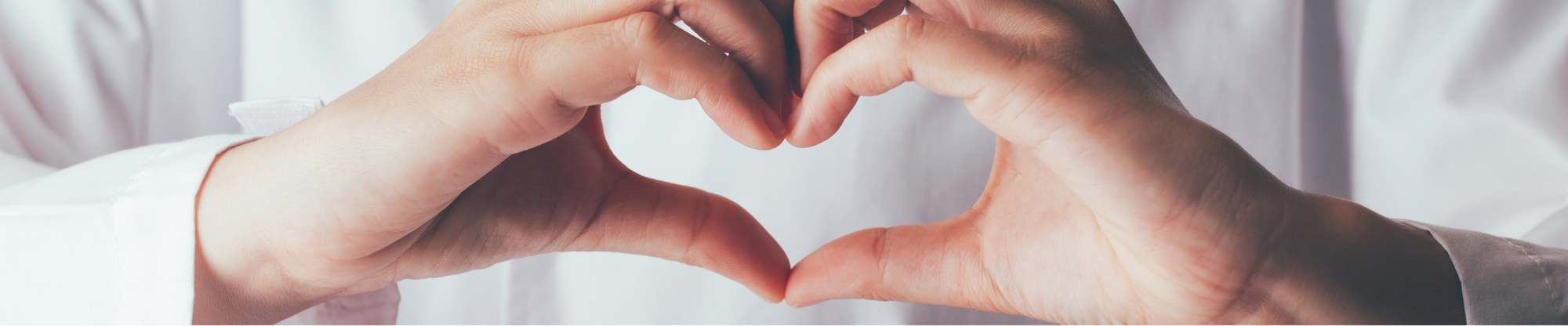 close up of medical professional with hands making a heart shape on their chest