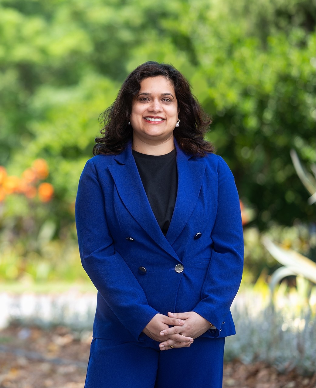 Profile of Payal Tiwari Greens candidate for Holt. Payal is wearing in a blue suit and is standing in front of parkland.