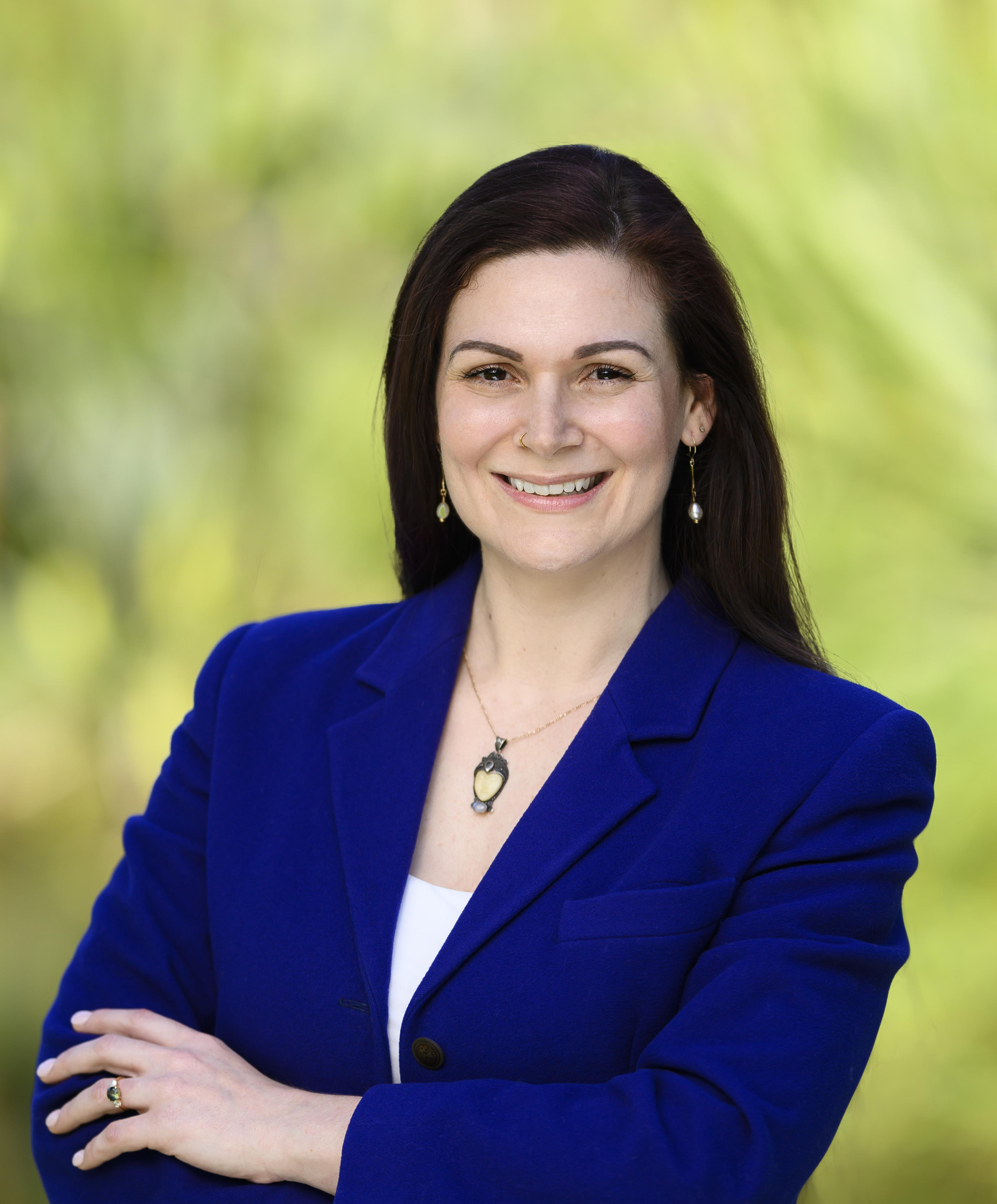 Greens state candidate Kim Samiotis stands against a background of trees.