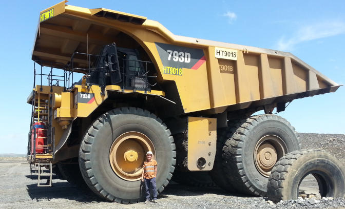 Will standing next to wheel of very large mine truck