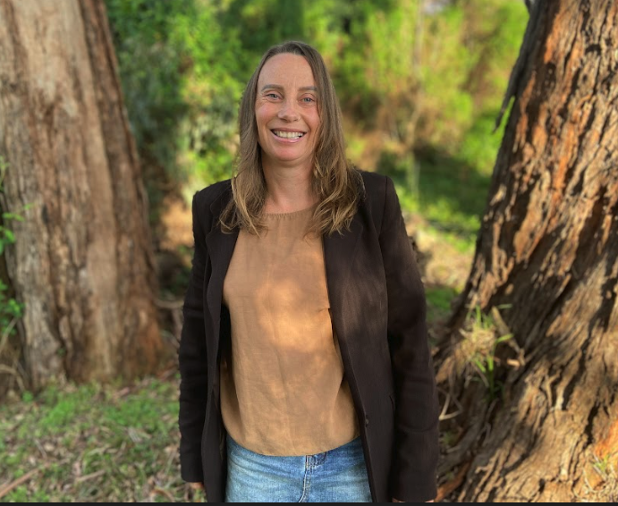 Greens state candidate Rochelle Hine stands against a background of trees.