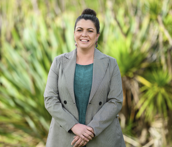 Greens state candidate Alysia Regan stands against a background of trees.