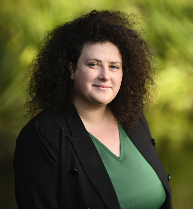 Greens state candidate Rachel Iampolski stands against a background of trees.