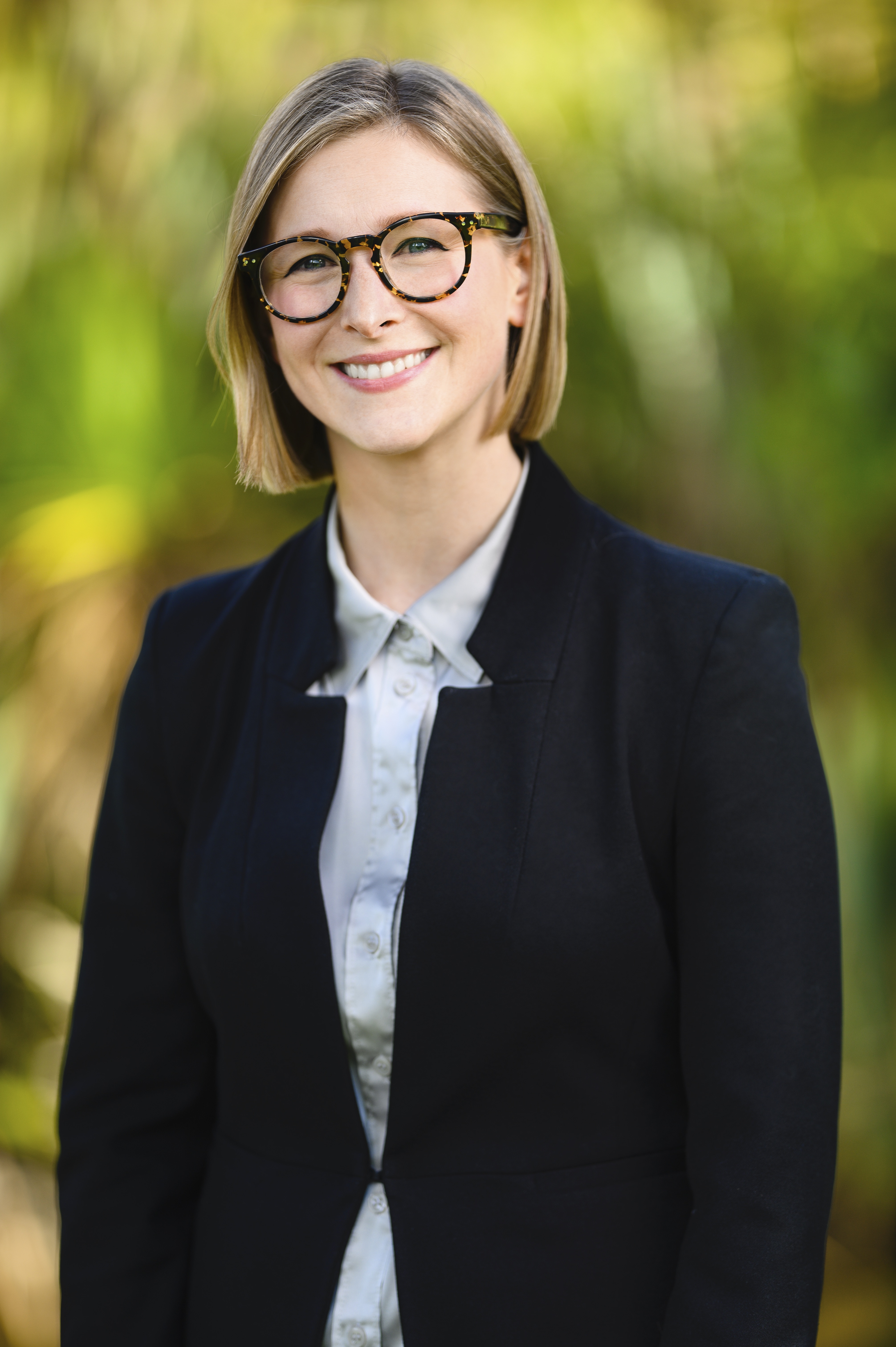 Greens state candidate Sarah Dekiere stands against a background of trees.