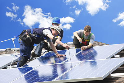 Image of three people on a roof installing solar panels